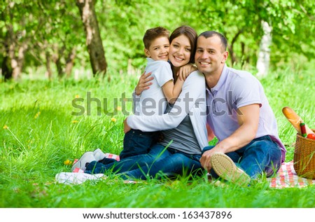 Family Of Three Has Picnic In Park. Concept Of Happy Family Relations And Carefree Leisure Time