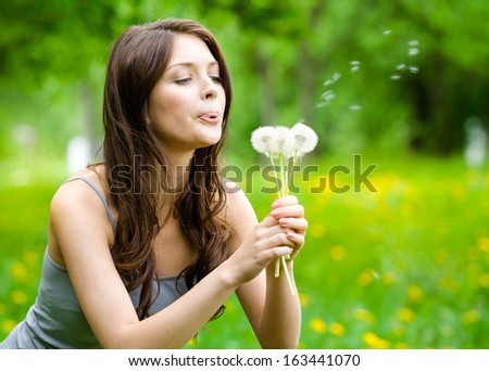 Woman Blows Dandelions In The Park. Concept Of Nature And Rest