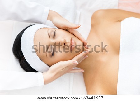 Portrait of half-naked woman with closed eyes getting face massage. Concept of relax and medicine