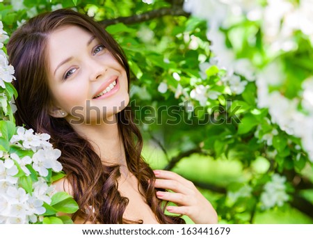 Portrait Of Pretty Girl Near The Flowered Tree In The Park. Concept Of Youth And Natural Beauty