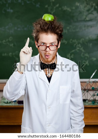 Crazy scientist with a green apple on his head shows forefinger