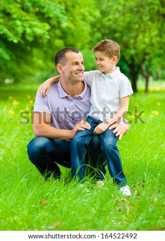 Father keeps son on the knee in the park. Concept of happy family relations and carefree leisure time