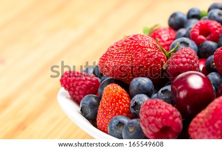 Close up of plate full of berries on the table. Concept of healthy eating and dieting lifestyle