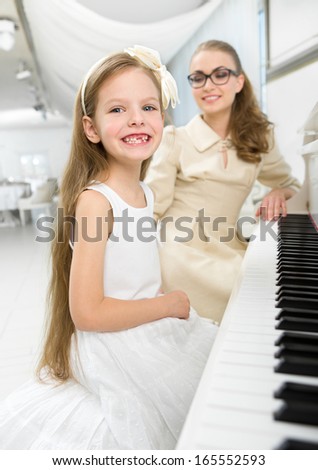 Master teaches little girl to play piano. Concept of music study and art