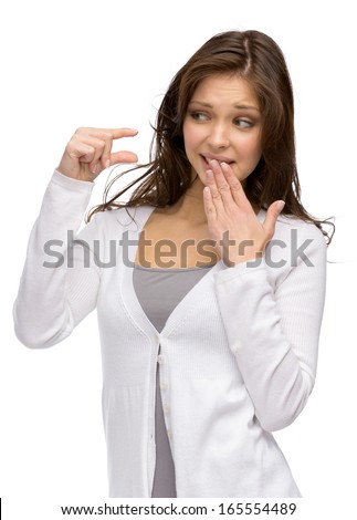 Half-length portrait of woman showing small amount of something and covering mouth with a hand, isolated on white
