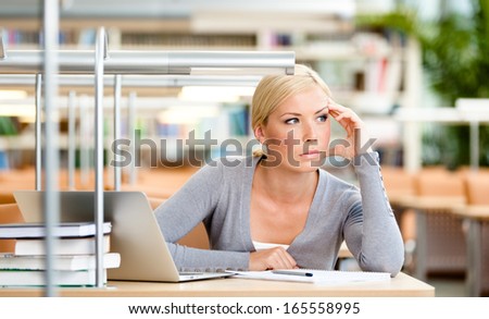 Female student working on the laptop sitting at the desk. Process of studying