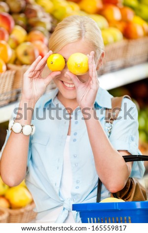Girl at the shop choosing fruits and vegetables hands lemons and full of purchases hand cart