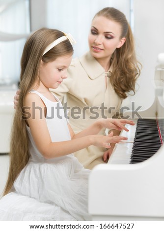 Master teaches little girl to play piano. Concept of music study and arts