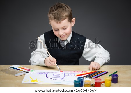 Portrait of child painting something with paints and pencils. Concept of arts and hobby