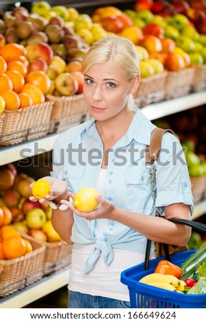 Girl at the market choosing fruits and vegetables hands lemons and full of purchases hand cart