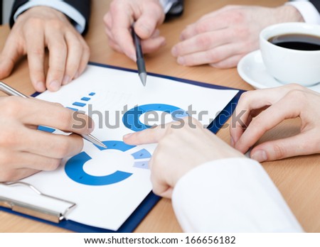 Close up of pointing at the graph hands of managers discussing and sitting at the table