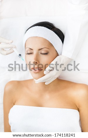 Woman with closed eyes gets injections on face. Concept of plastic surgery and beauty