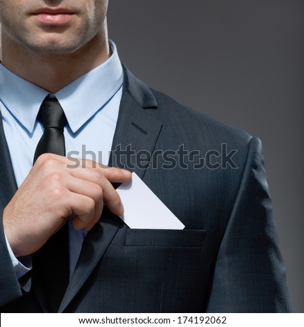 Part of body of man who takes out business card from the pocket of business suit, copyspace