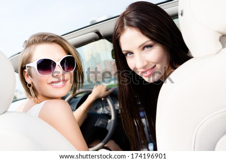 Two girls ride the car. Teenagers have a little trip on vacation