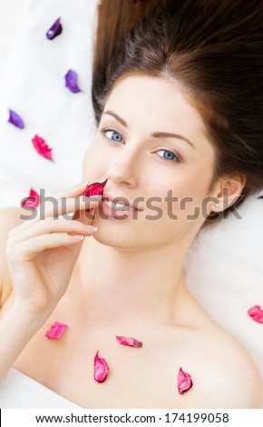 Portrait of half-naked woman lying in petals of flowers. Concept of care and youth