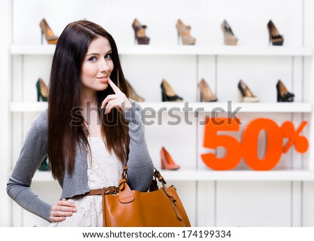 Portrait of woman in shopping center with 50% sale in the section of female heeled shoes. Concept of consumerism and stylish purchase