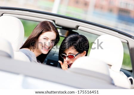 Two happy girls sitting in the car turn back and have fun while having little car trip