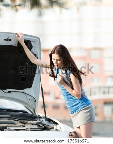 Woman repairing the broken car on the highway. Girl stands near opened bonnet of the car after an accident