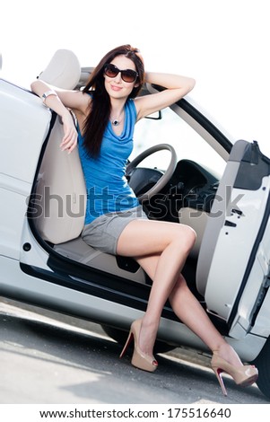 Pretty woman in sunglasses sits in the cabriolet with door opened