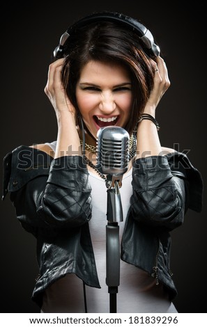 Half-length portrait of female rock musician with microphone and earphones. Concept of rock music and rave