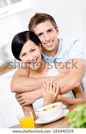 Male hugs his smiley girlfriend in the kitchen