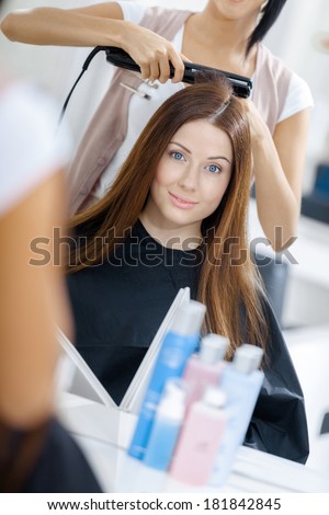 Reflection of beautician doing hair style for woman in hairdresser\'s. Concept of fashion and beauty