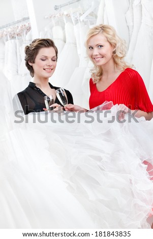 Two girls drink spirits while discussing and choosing the wedding gown