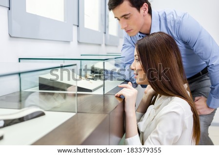 Girl with man chooses expensive jewelry at jeweler\'s shop. Concept of wealth and luxurious life