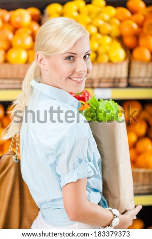 Girl hands bag with fresh vegetables against the shelves of fruits in the store