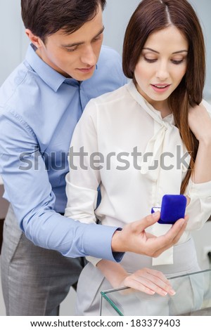 Man presents engagement ring to his girl at jeweler\'s shop. Concept of wealth and luxurious life