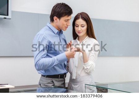 Male presents engagement ring to his girl at jeweler\'s shop. Concept of wealth and luxurious life