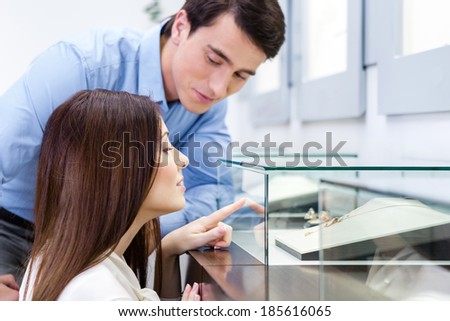 Girl with male selects expensive jewelry at jeweler\'s shop. Concept of wealth and luxurious life