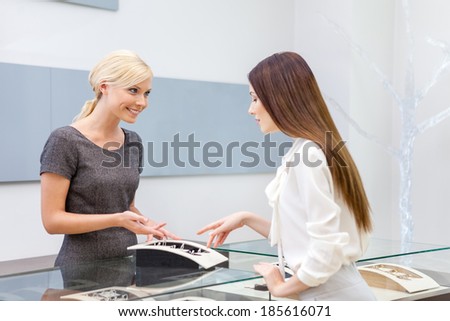 Salesperson helps lady to choose jewelry at jeweler\'s shop. Concept of wealth and luxurious life