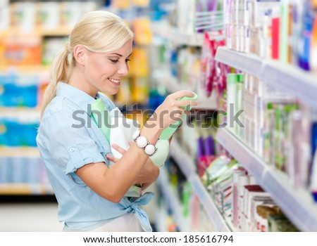 Girl at the shop purchasing cosmetics among the great variety of products. Concept of consumerism, retail and purchase