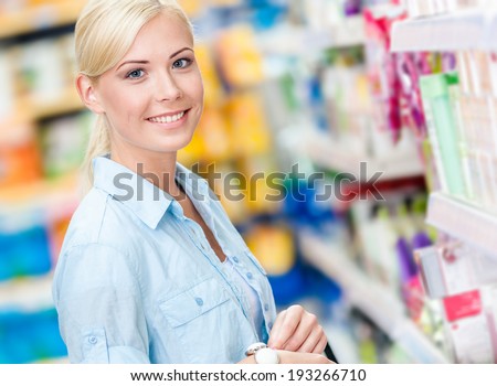 Portrait of young girl at the shop standing near the shelves with cosmetics
