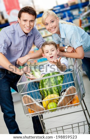 Family drives cart with food and son sitting there with watermelon. Concept of fresh and healthy food and consumerism