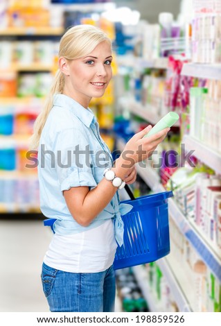 Half length portrait of girl at the market choosing cosmetics among the great variety of products. Concept of consumerism, retail and purchase