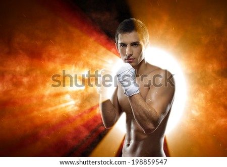 Half-length portrait of working out fighter with hands wrapped with elastic bandage against exploding sun