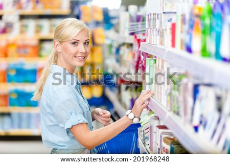 Side view of girl at the shop choosing cosmetics among the great variety of products. Concept of consumerism, retail and purchase