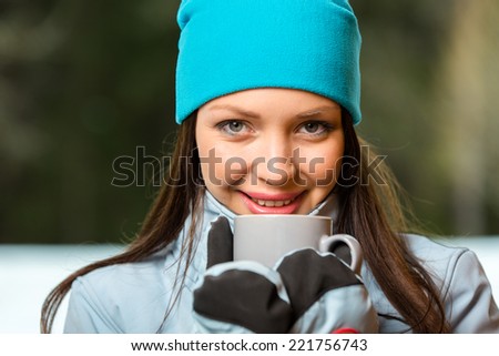 Portrait of female drinking hot tea and wearing warm clothes outdoors when going in for winter sports