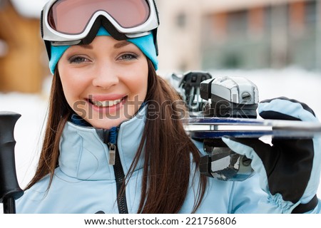 Close up of woman wearing sports jacket and goggles who hands skis