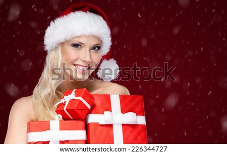Beautiful lady in Christmas cap holds a set of gifts wrapped with red paper, isolated on purple