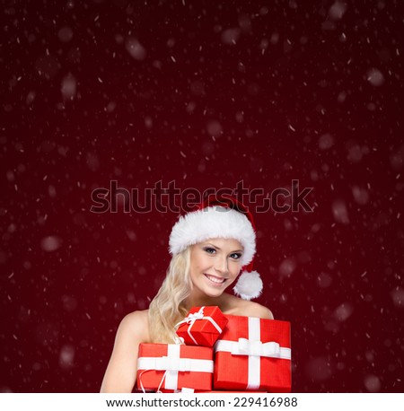Beautiful girl in Christmas cap holds a set of gifts wrapped with red paper, isolated on purple