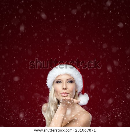 Beautiful woman in Christmas cap blows kiss, purple background