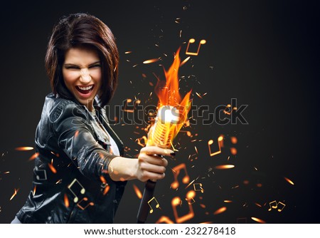 Half-length portrait of female rock musician handing mike on fire, grey background