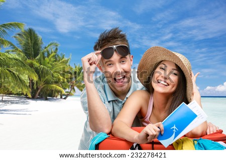 Couple packs up suitcase with clothing for honeymoon trip, tropical beach background. Concept of romantic vacations and lovely honeymoon