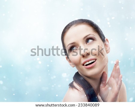 Woman applying face cream in to have smooth perfect skin, snowy background. Body care concept