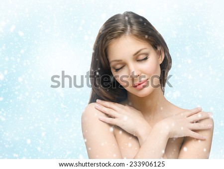 Attractive girl with eyes closed touching her body on winter background. Concept of beauty and youth