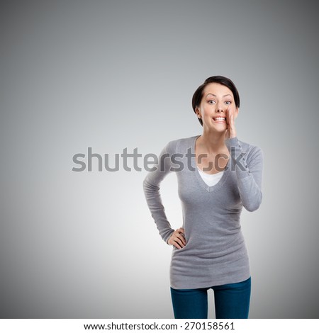 Pretty woman whispers, isolated on grey background