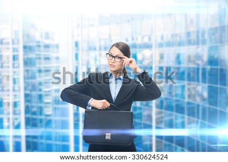 Portrait of business woman keeping case, blue background. Concept of leadership and success